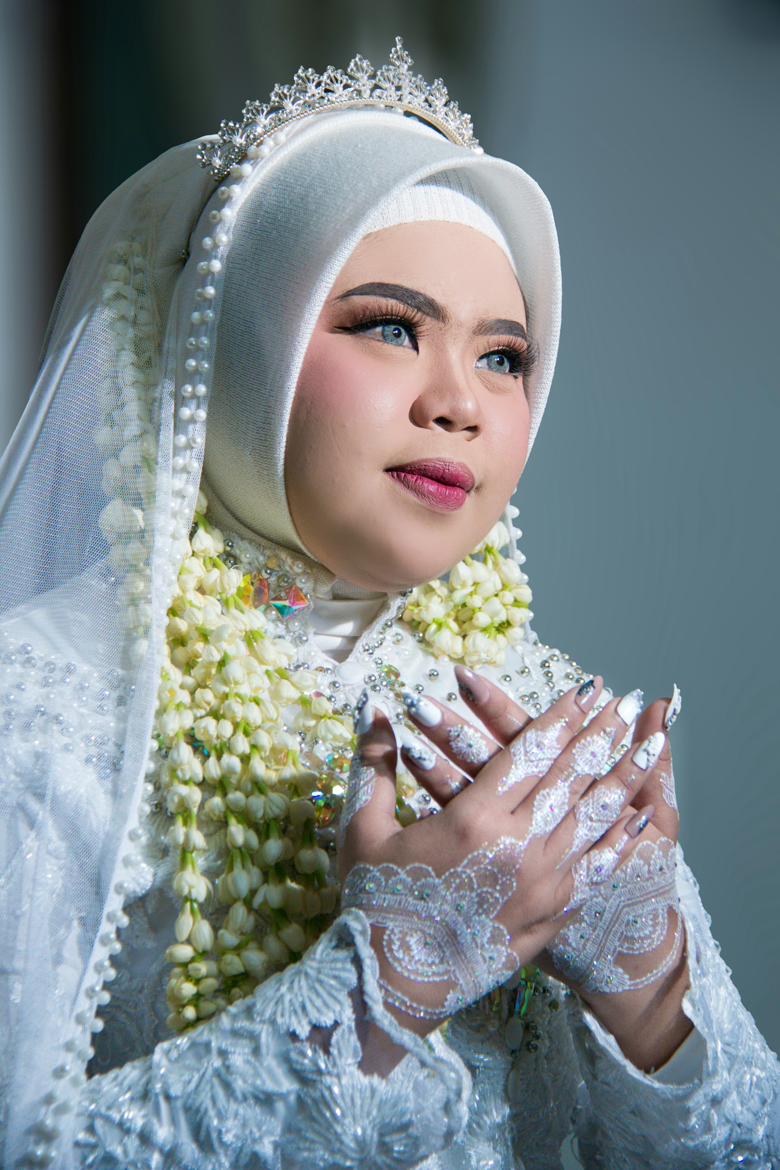Bride in white hijab with floral garland and henna at an Islamic wedding
